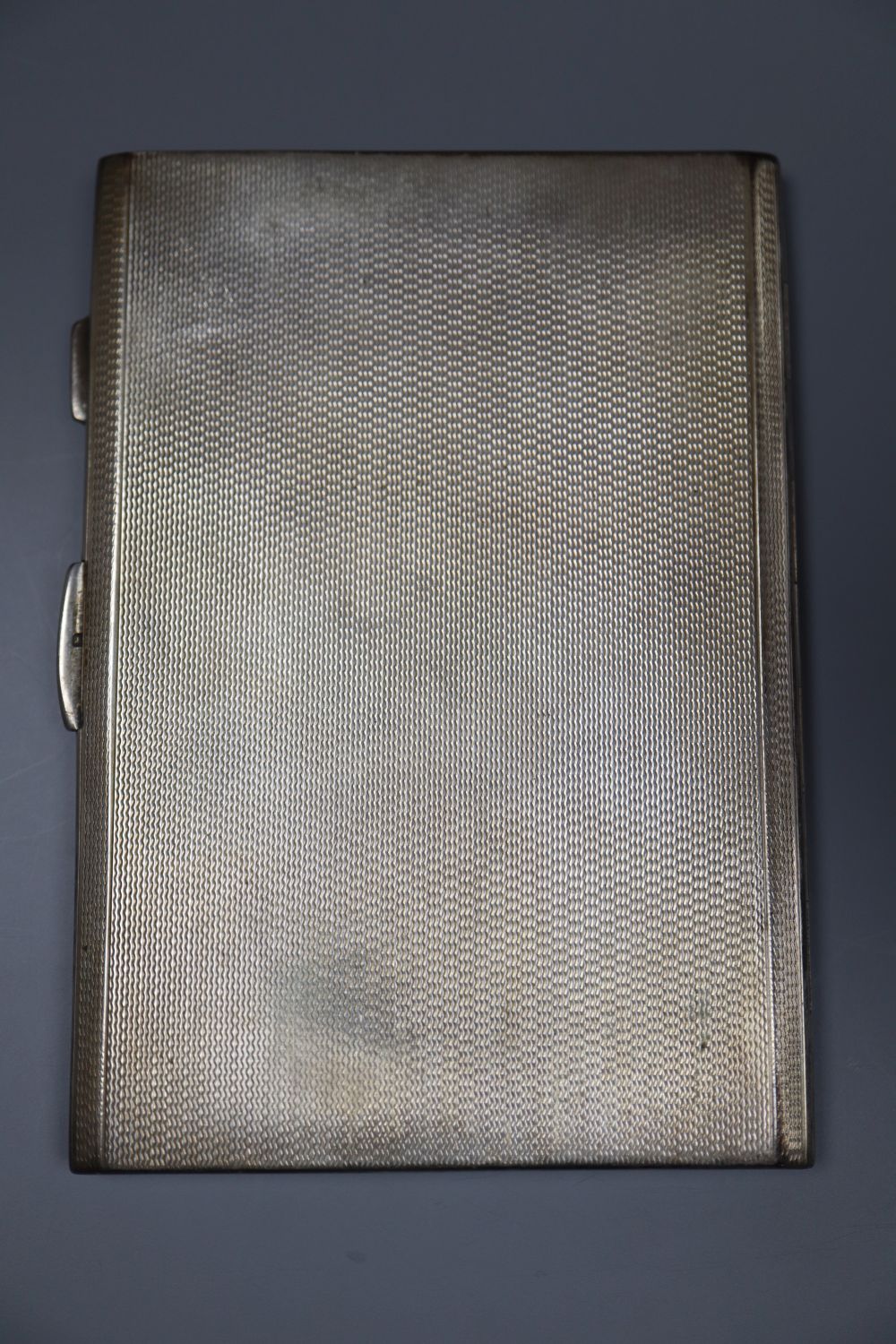 Three assorted mid 20th century silver engine turned cigarette cases, largest 16.8cm, gross 18oz.